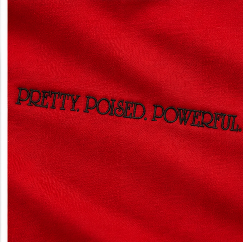 Close-up of black PRETTY POISED POWERFUL embroidery on red tee